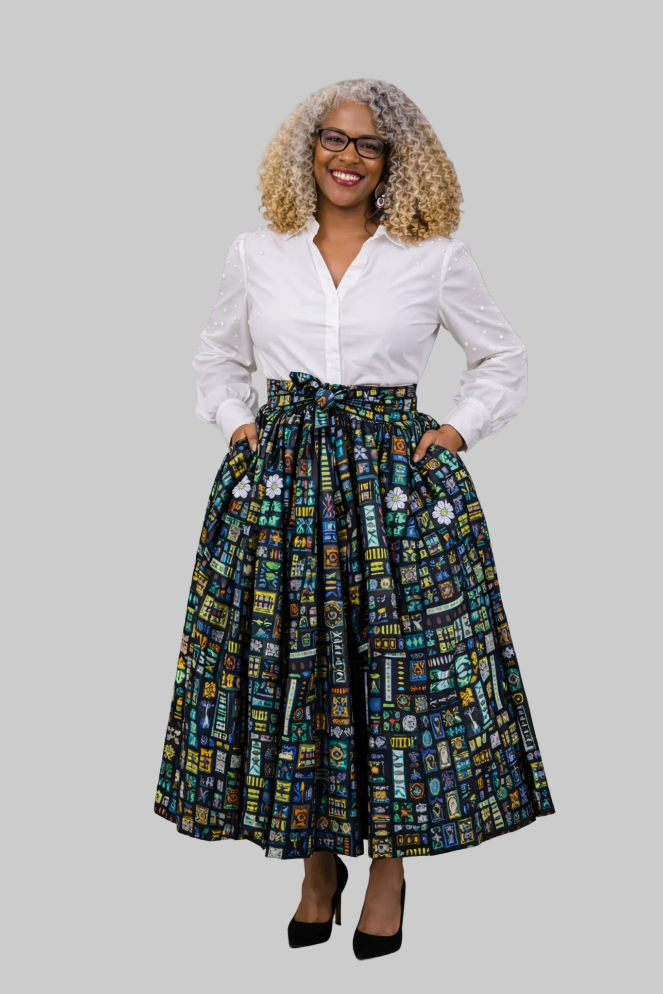 Woman wearing a white blouse and patterned skirt against a gray background