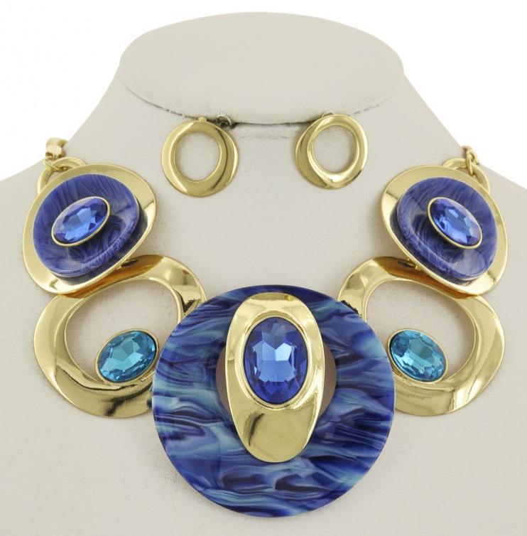 A royal blue and gold bejeweled statement necklace displayed with ornate gold metal and large royal blue stones. gold earings.