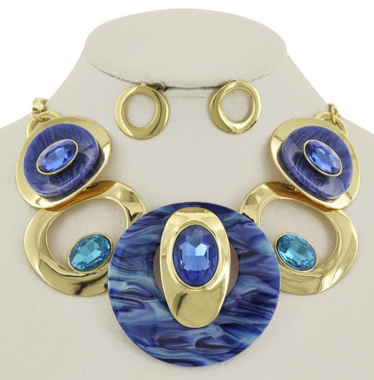 A royal blue and gold bejeweled statement necklace displayed with ornate gold metal and large royal blue stones. gold earings.