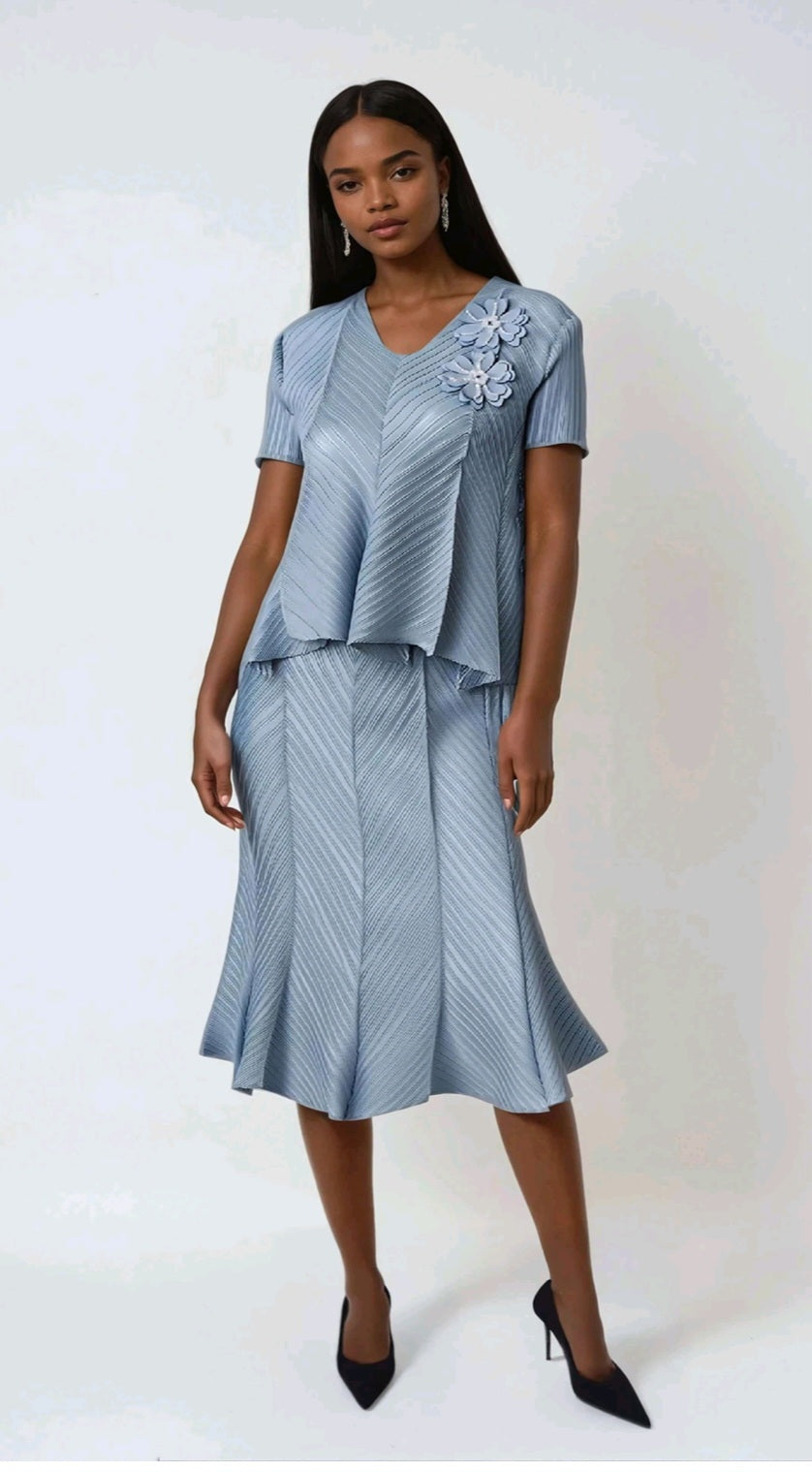 Woman wearing a light blue dress with a floral embellishment on a white background