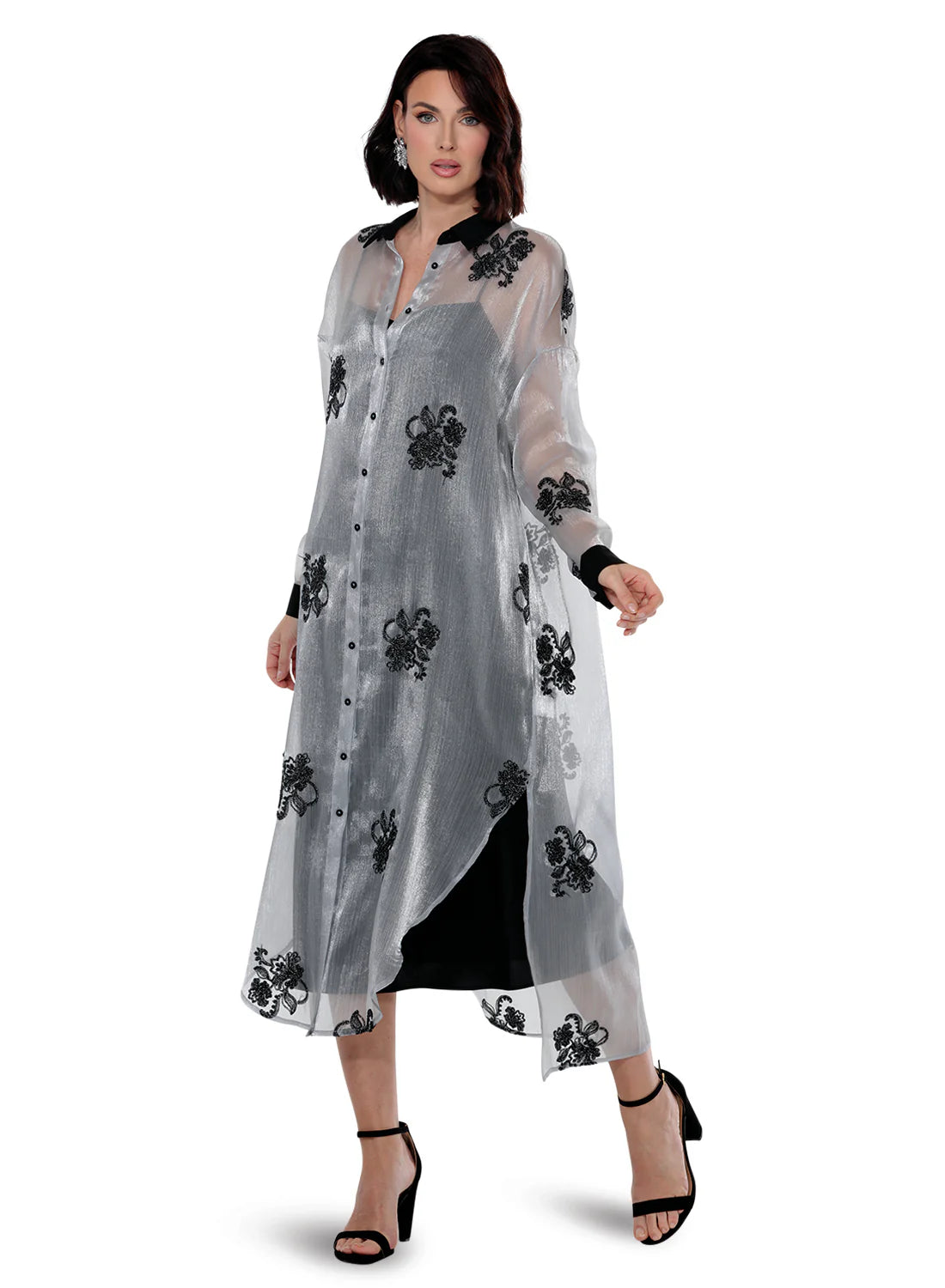 A woman models the Midnight Bloom Sheer Embroidered Duster, featuring a silver sheer fabric with black floral embroidery, a black pointed collar, and cuffs.