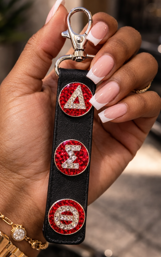 Hand holding a keychain with red and rhinestone delta sigma theta in Greek letter on a rectangle leather key chain base