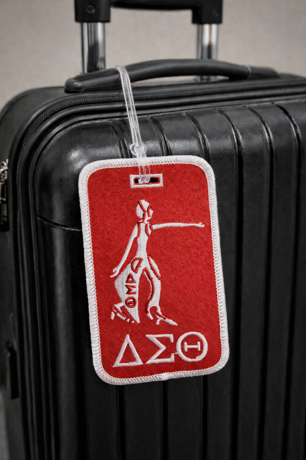 Lady Fortitude Red and white luggage tag with a symbol on a black suitcase