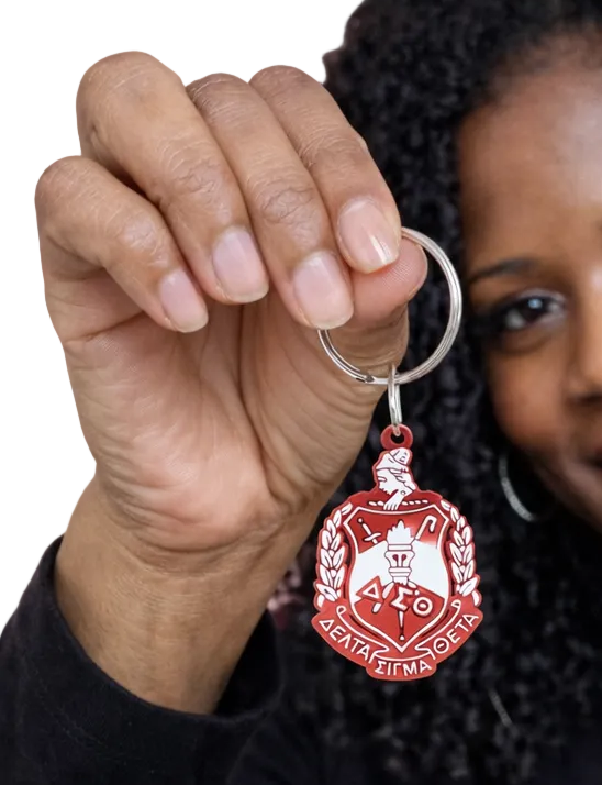 Person holding a red  DST crest keychain  against a white background