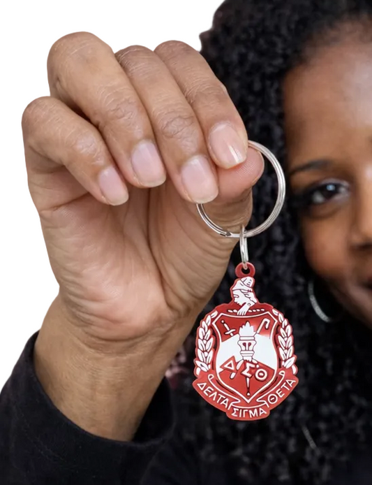Person holding a red  DST crest keychain  against a white background