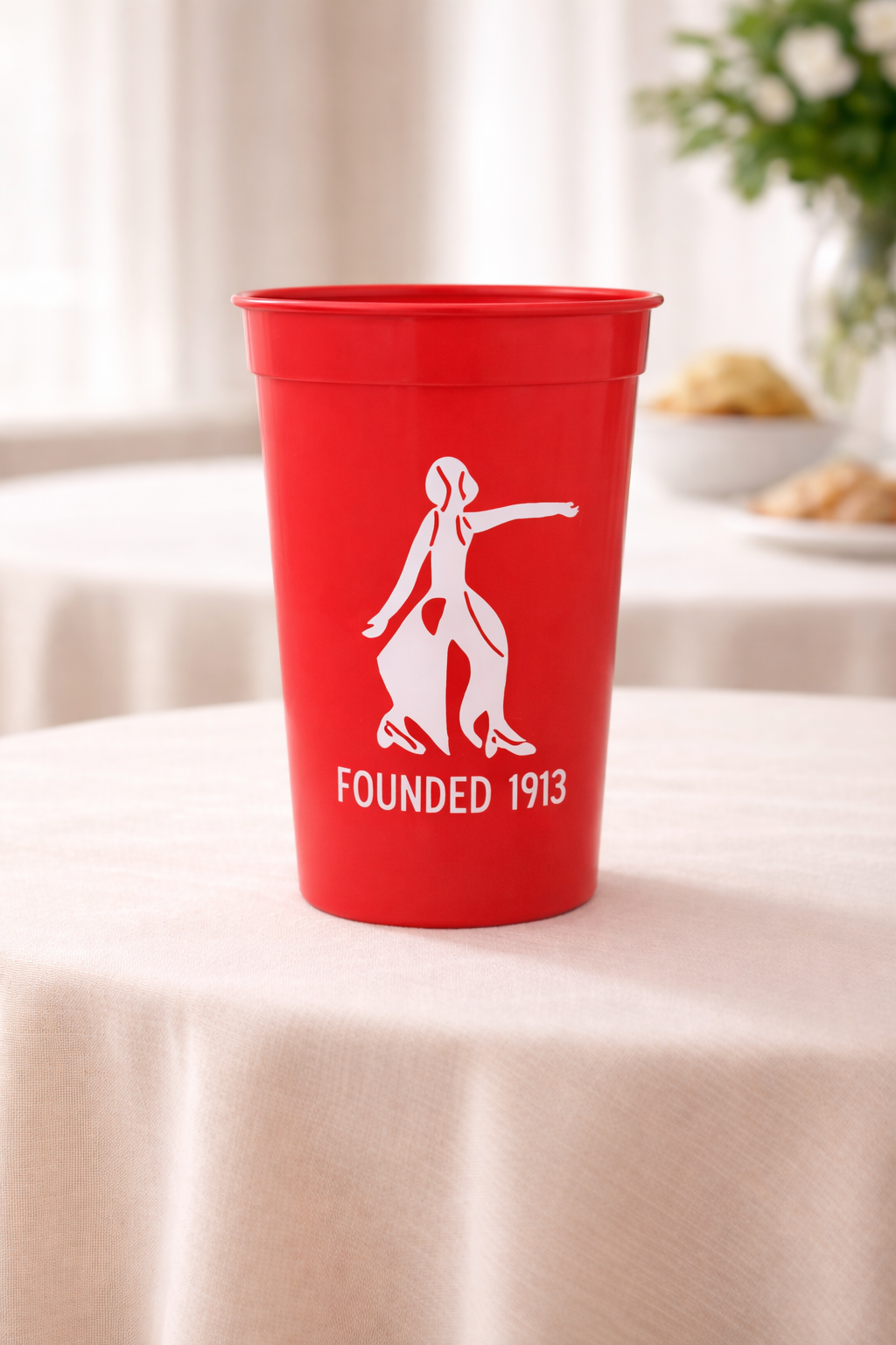 Red cup with white lady fortitude  and text 'Founded 1913' on a light surface.