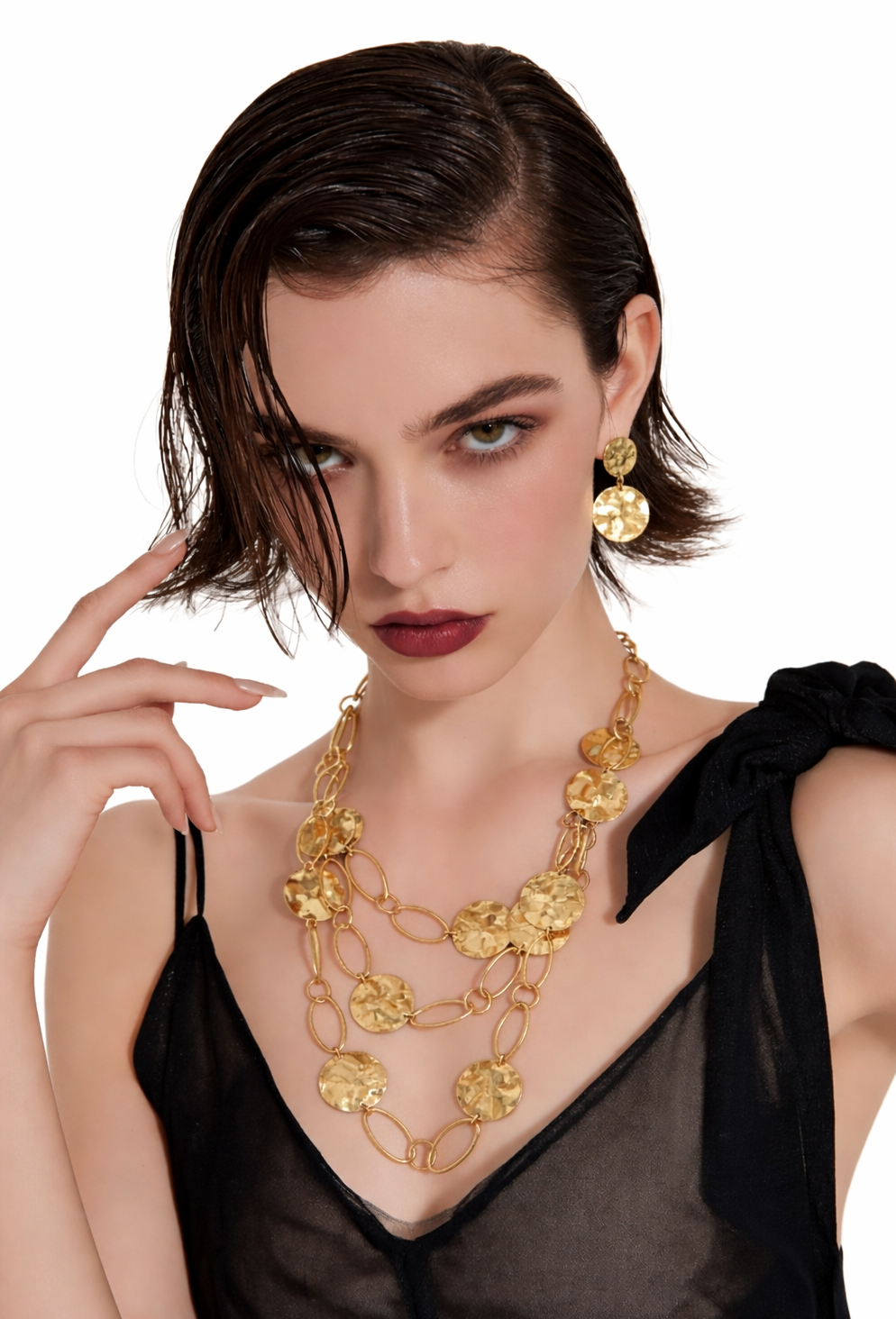 Woman wearing a gold necklace and earrings on a white background