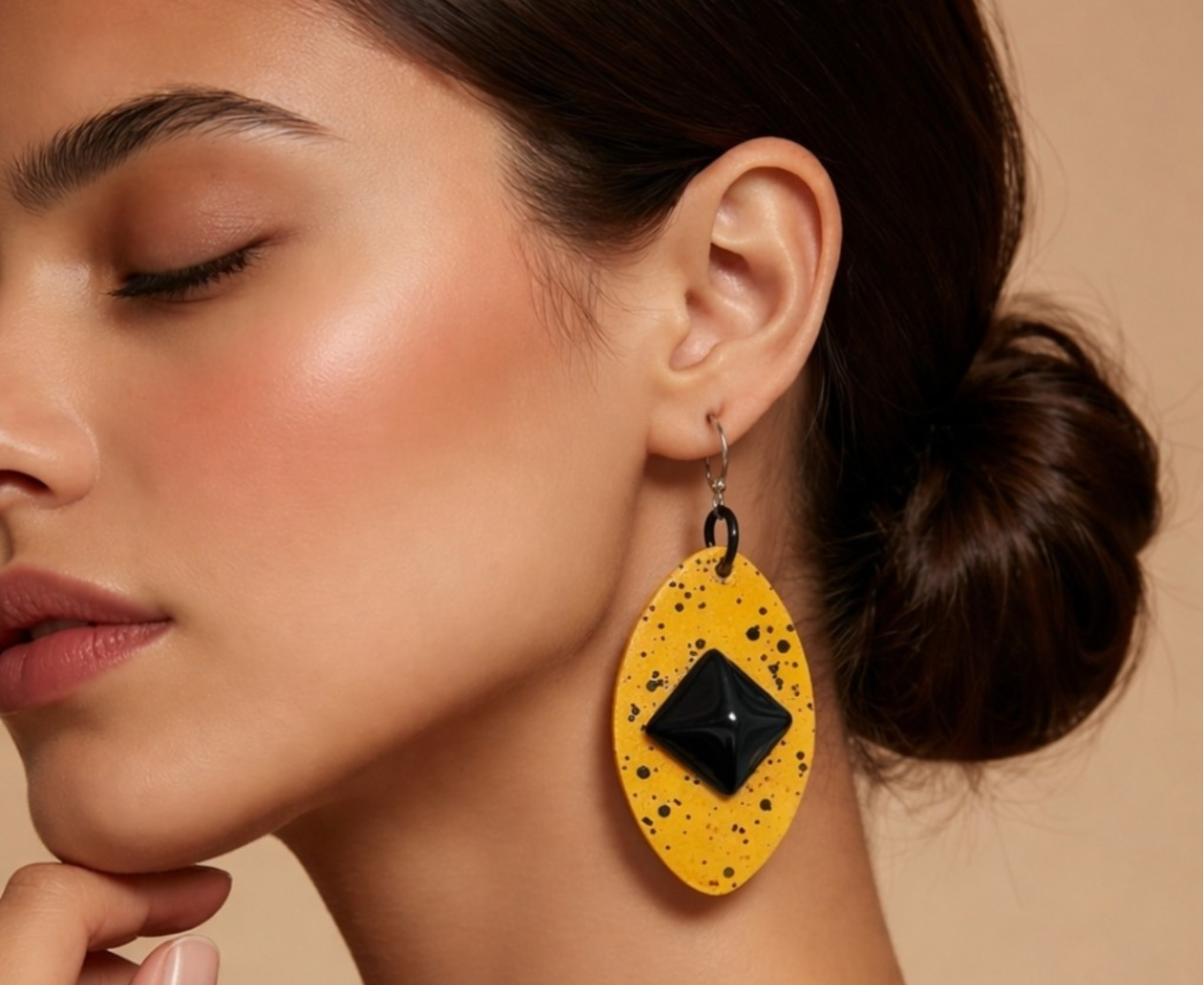 Woman wearing yellow earrings with a black center on a beige background