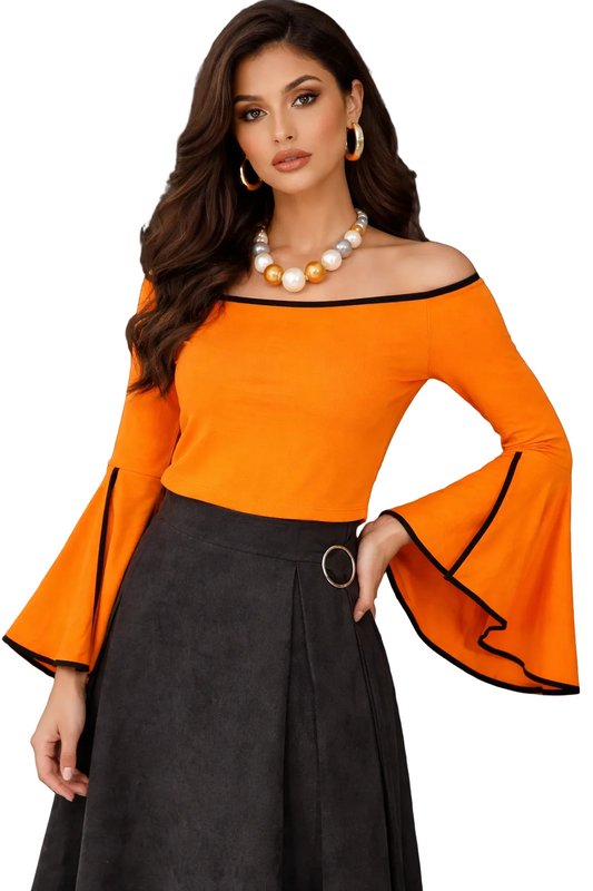 Woman wearing an orange off-shoulder top with black trim and a black skirt, standing against a textured wall.
