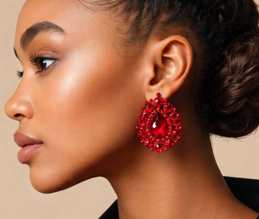Close-up of a woman wearing red gemstone earrings against a neutral background