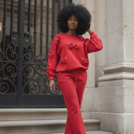 Woman wearing a red outfit with rhinestone embellished bow detail standing on steps