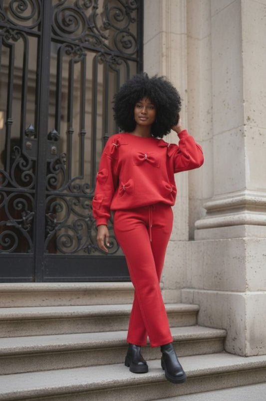 Woman wearing a red outfit with rhinestone embellished bow detail standing on steps