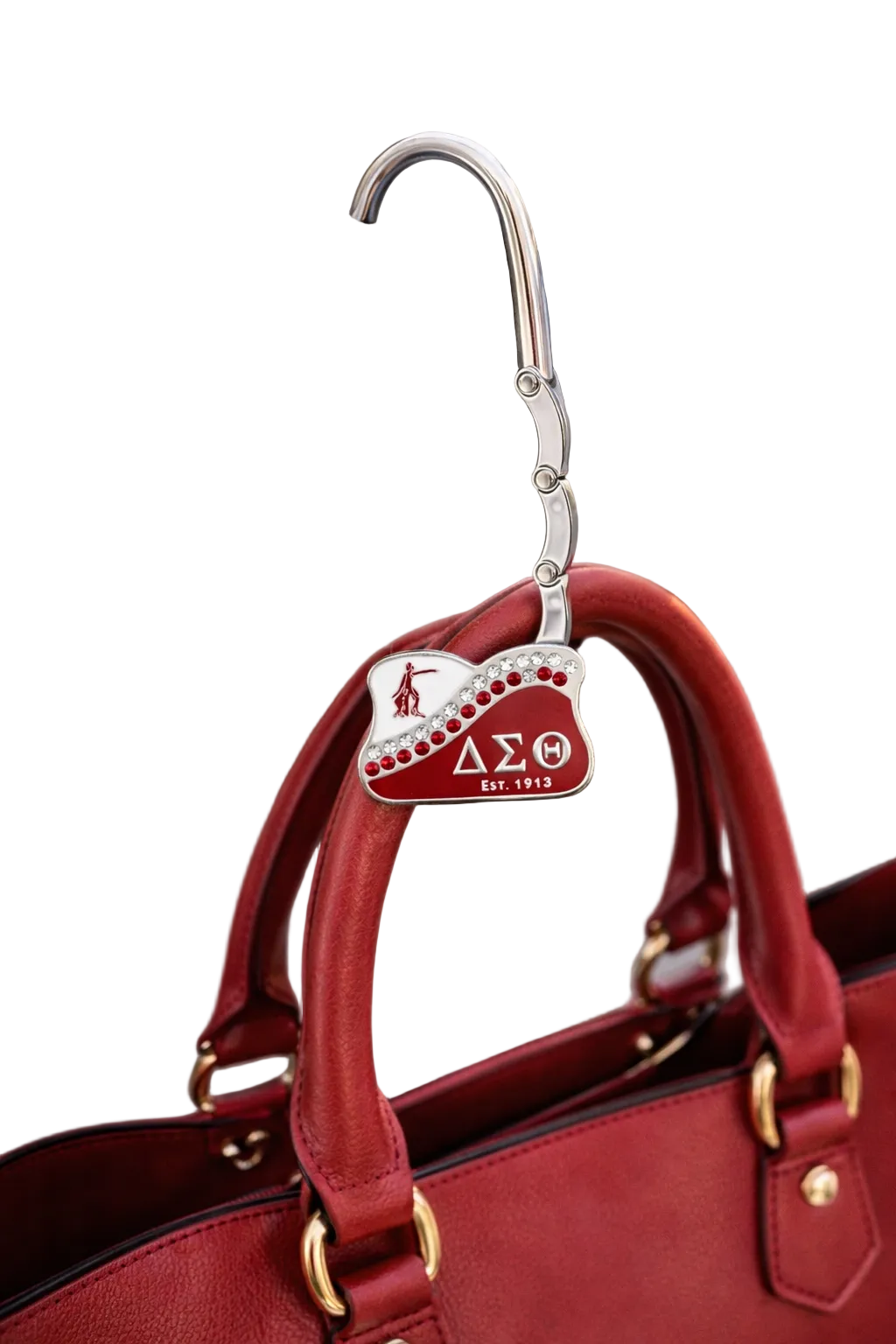 Red handbag with a Delta Sigma Theta keychain attached, hanging on a metal railing.