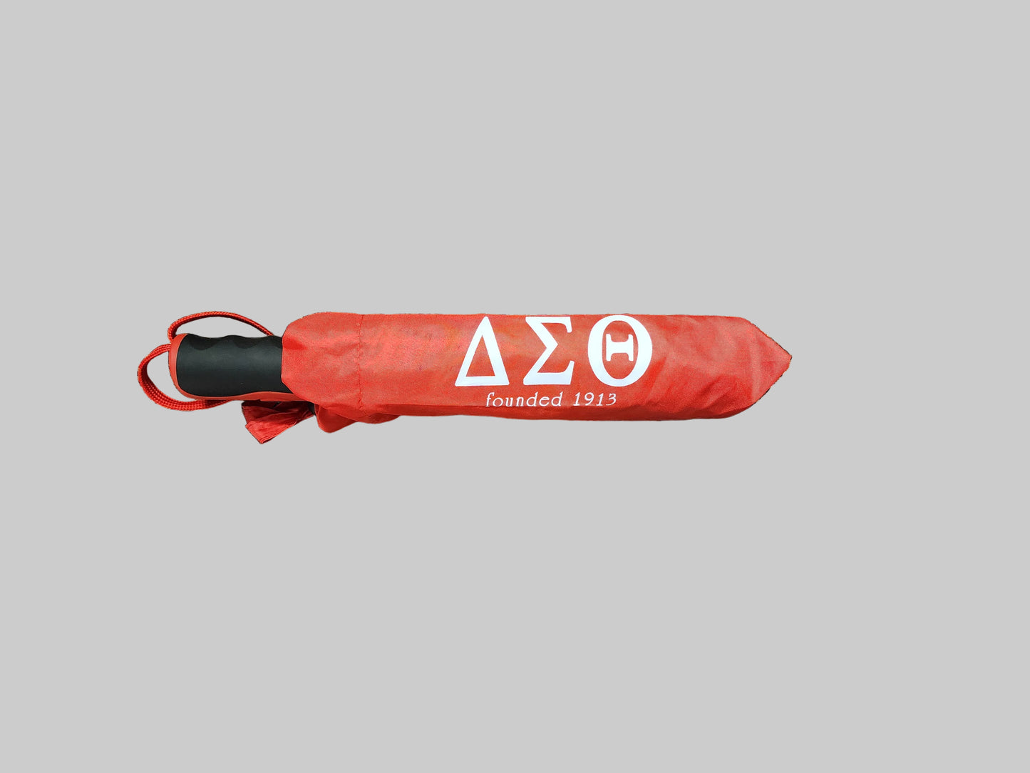 Red folded umbrella with Delta Sigma Theta logo on a gray background