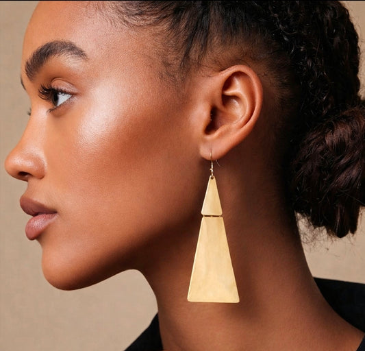 Close-up of a woman wearing a gold geometric earring against a neutral background